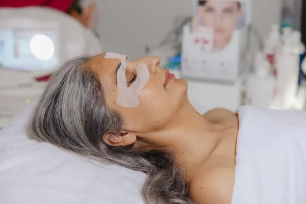 Applying a facial mask during a beauty treatment session, individual receiving skincare services