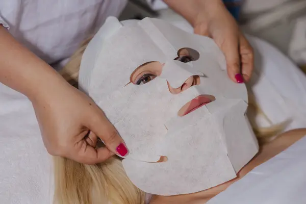 Skincare therapist applying a professional carboxy facial mask to a client’s face to boost oxygenation, improve skin radiance, and enhance overall complexion during a spa treatment.